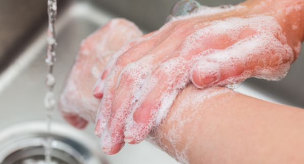 Soapy hands being washed over sink 