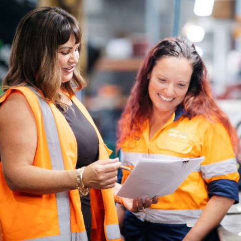 Broker talking to client look at paper wearing orange vests 