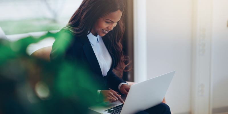 Woman in corporate attire sitting looking at her laptop